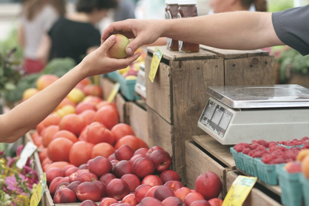 Dos manos dandose una manzana en un mercado